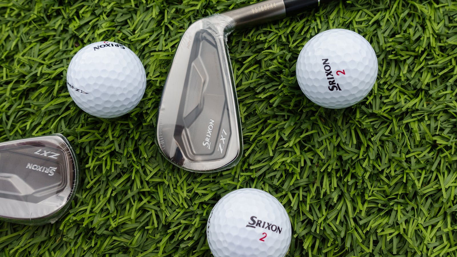 Golf clubs and balls arranged on vibrant green grass, perfect for sports enthusiasts.